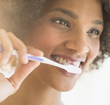 Close-up of someine brushing and flossing their teeth as part of a daily routine.