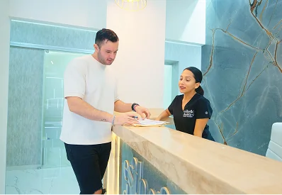Dentist consulting with patient at reception desk at the clinic.