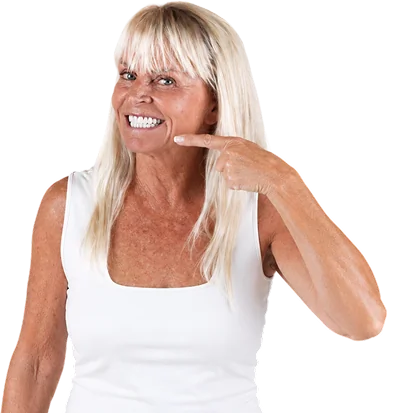 Older woman smiling and pointing at her bright results of All-on-4 treatment.