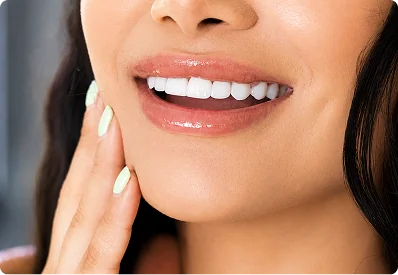 Close up picture of woman smiling with veneers while touching her face